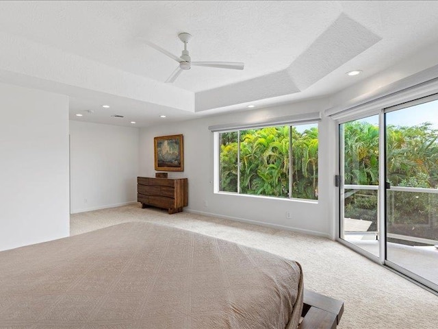 unfurnished bedroom featuring access to outside, multiple windows, ceiling fan, and a raised ceiling