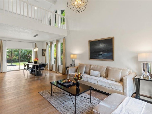 living room featuring a notable chandelier, a towering ceiling, and light hardwood / wood-style floors