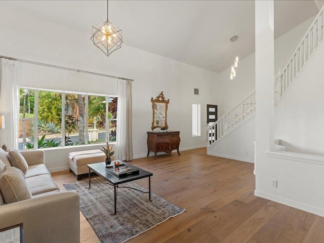 living room with hardwood / wood-style floors, an inviting chandelier, and high vaulted ceiling