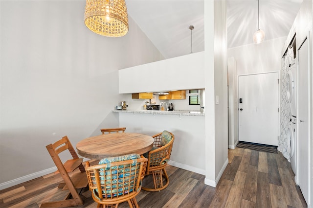 15 Kulanihakoi St Unit 9F, Kihei, HI 96753 - dining area with high vaulted ceiling, baseboards, dark wood-style flooring, washer / clothes dryer, and a chandelier