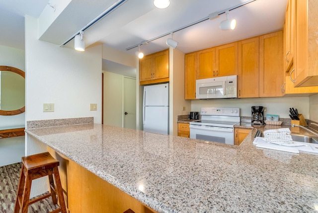 kitchen with kitchen peninsula, white appliances, track lighting, and light stone countertops