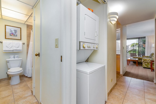 washroom featuring stacked washer / dryer and light tile floors