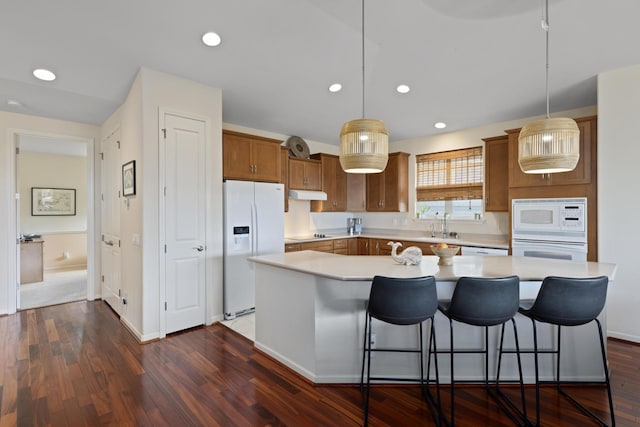 kitchen with a center island, white appliances, and decorative light fixtures