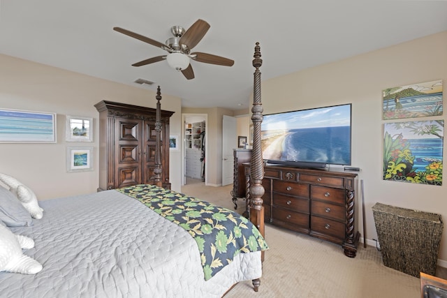carpeted bedroom featuring ceiling fan and a walk in closet
