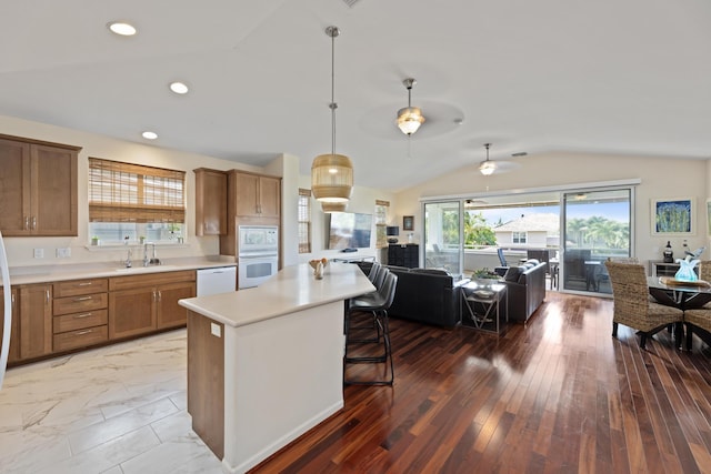 kitchen with sink, white appliances, a breakfast bar area, a kitchen island, and vaulted ceiling