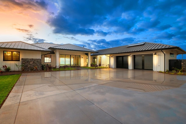 view of front facade with a garage, a standing seam roof, metal roof, and concrete driveway