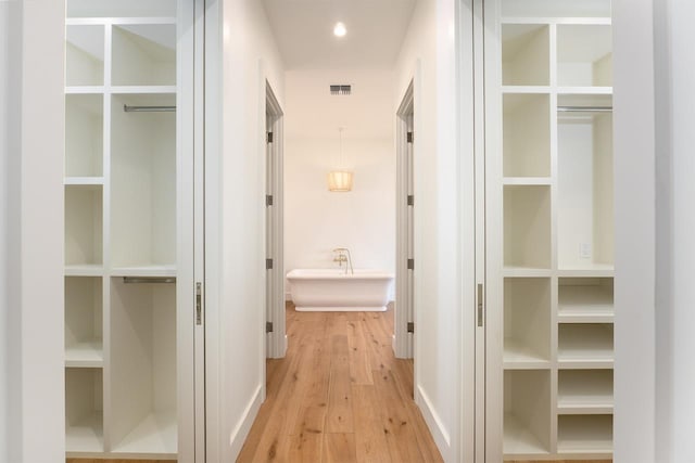 hallway featuring light wood-type flooring, visible vents, and recessed lighting