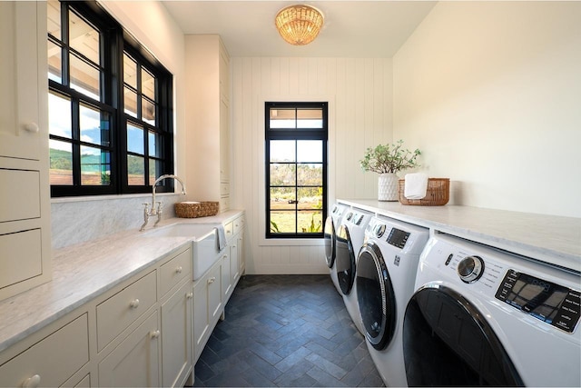 laundry room with cabinet space, washing machine and dryer, brick floor, and a sink