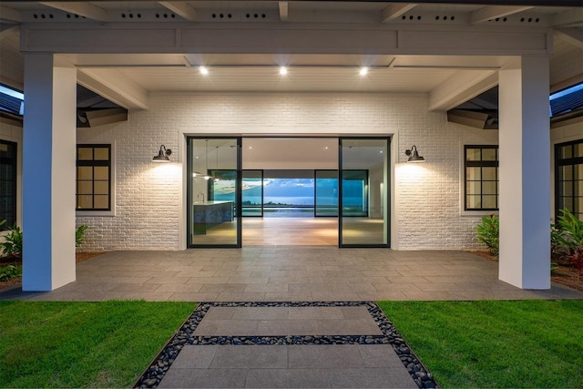 property entrance with a yard, a patio, and brick siding