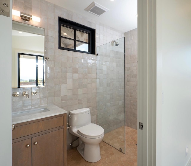 full bath with tile walls, visible vents, toilet, a tile shower, and vanity