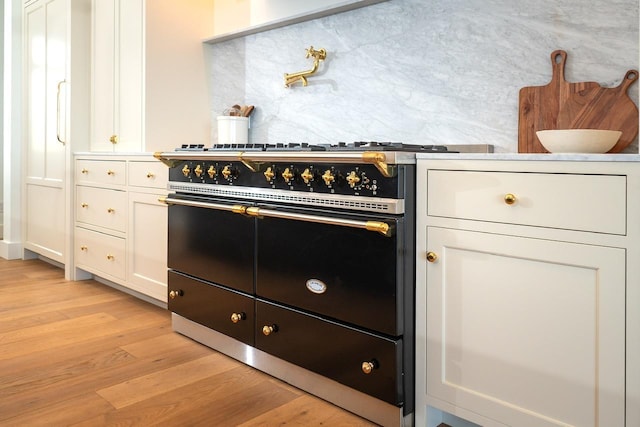 kitchen with white cabinets, light wood-style floors, double oven range, and decorative backsplash