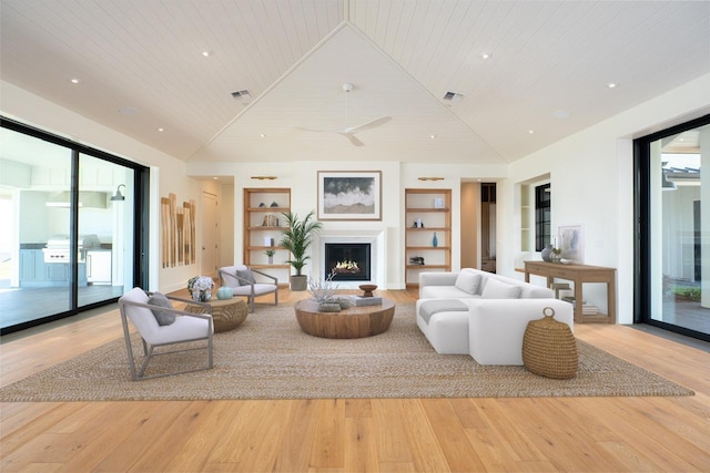 living room with built in shelves, wood-type flooring, visible vents, wooden ceiling, and a lit fireplace