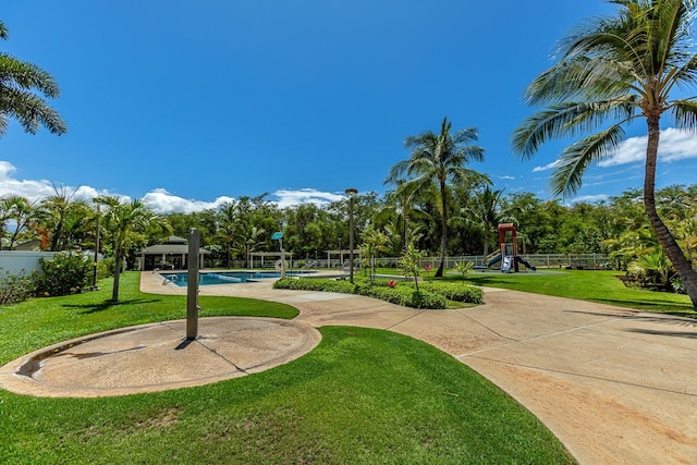 view of community featuring a playground, a yard, and a pool