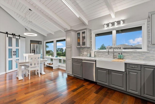 kitchen featuring gray cabinetry, sink, a barn door, tasteful backsplash, and stainless steel appliances