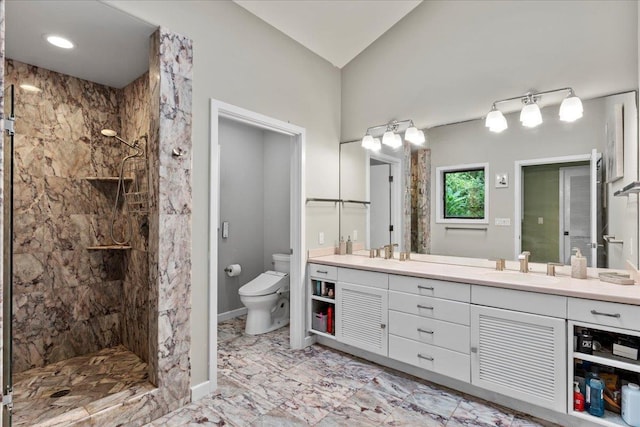 bathroom with vanity, toilet, and tiled shower