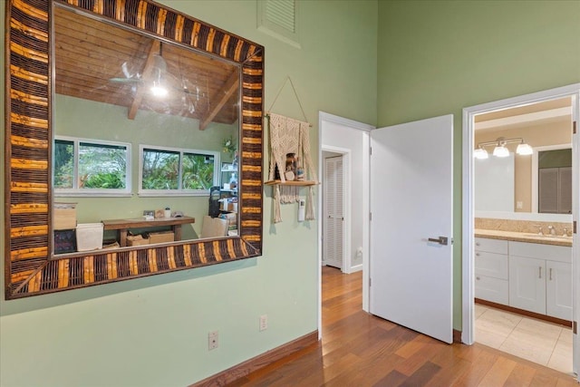 kitchen with white cabinets, wood-type flooring, sink, and beamed ceiling