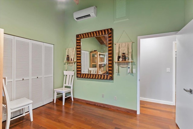 living area with hardwood / wood-style flooring and an AC wall unit