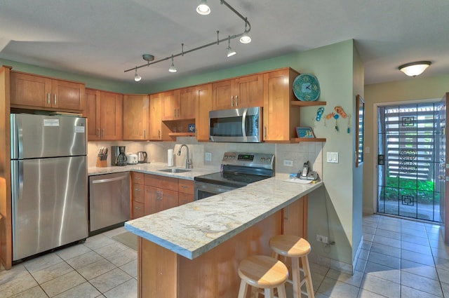 kitchen featuring a kitchen bar, kitchen peninsula, sink, and appliances with stainless steel finishes