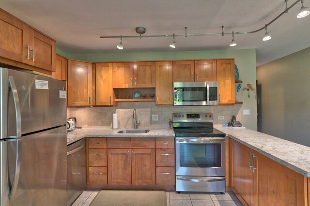 kitchen featuring kitchen peninsula, appliances with stainless steel finishes, tasteful backsplash, sink, and light tile patterned flooring