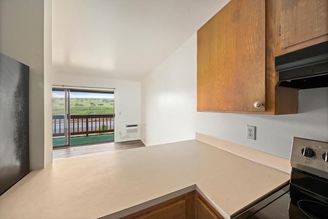 kitchen featuring lofted ceiling, an AC wall unit, electric stove, and wood-type flooring