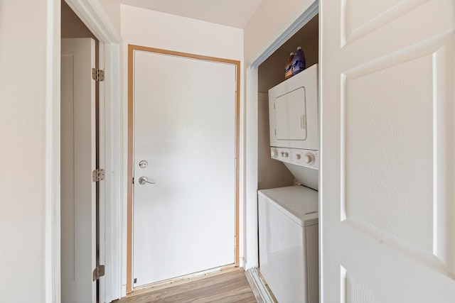 laundry room featuring light hardwood / wood-style floors and stacked washing maching and dryer