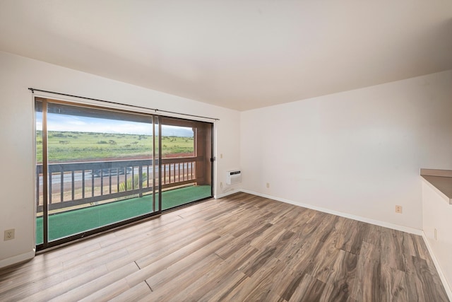 spare room with a wall mounted AC and light hardwood / wood-style floors