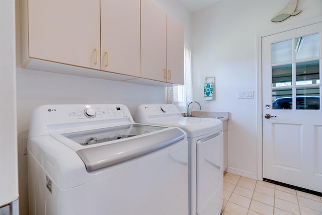 washroom featuring light tile patterned floors, washer and clothes dryer, cabinets, and sink