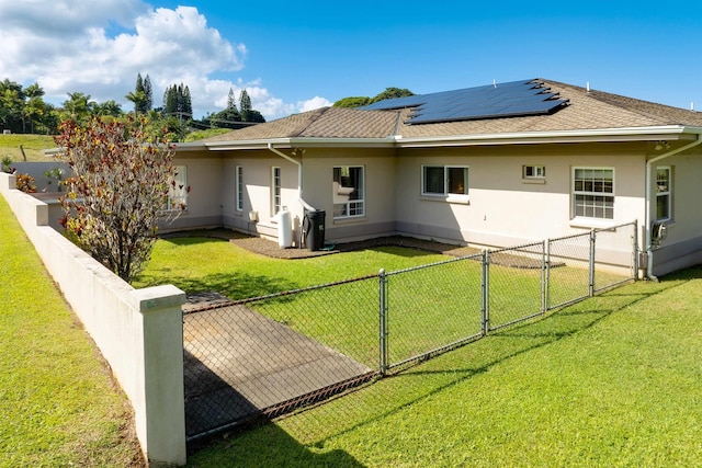 rear view of house featuring a yard and solar panels