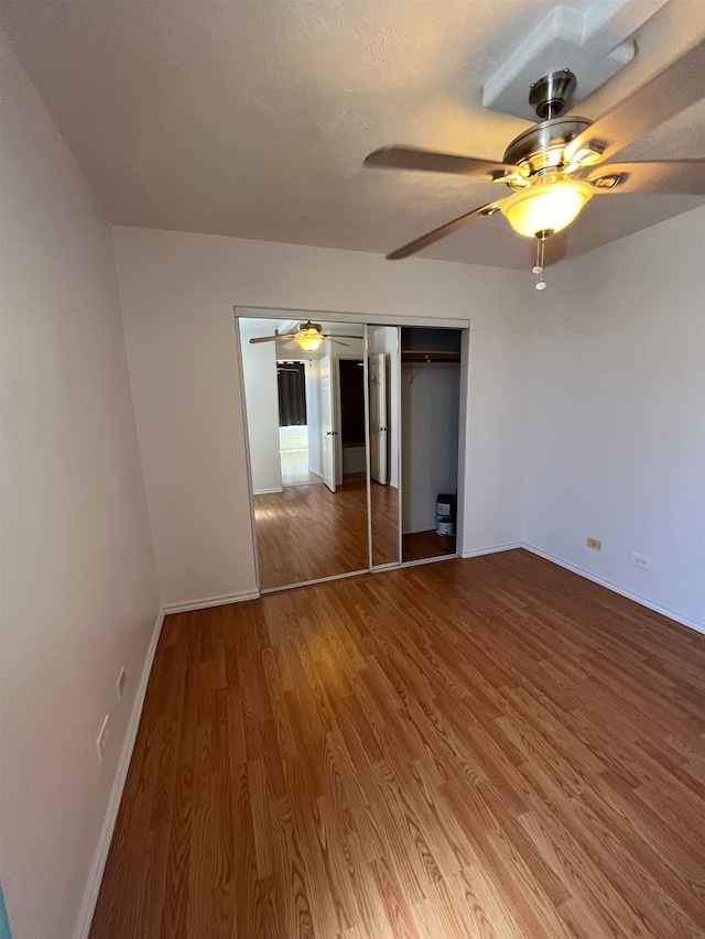 unfurnished bedroom with wood-type flooring, ceiling fan, and a closet