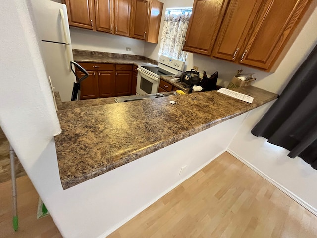 kitchen featuring white appliances, light hardwood / wood-style floors, kitchen peninsula, and sink