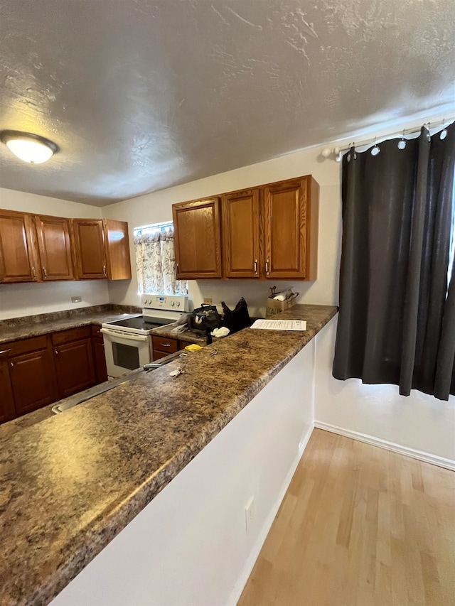 kitchen featuring light wood-type flooring, white electric range, and a textured ceiling