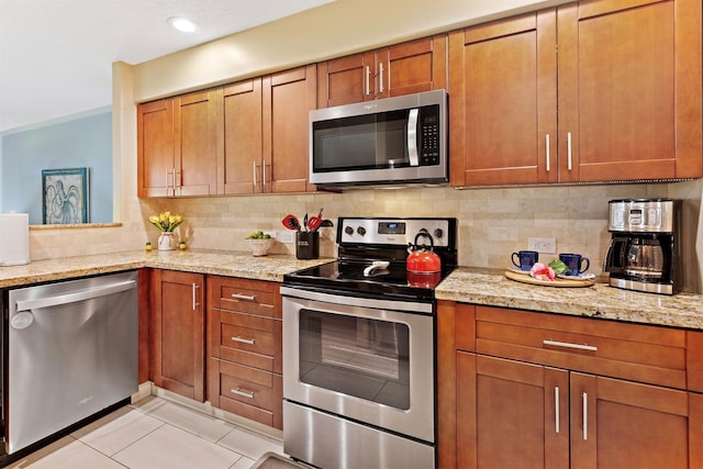 2560 Kekaa Dr Unit F 102, Lahaina, HI 96761 - kitchen featuring appliances with stainless steel finishes, brown cabinets, tasteful backsplash, and light stone counters