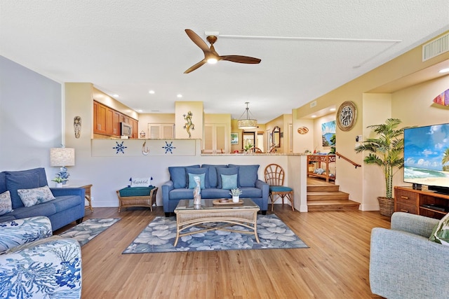2560 Kekaa Dr Unit F 102, Lahaina, HI 96761 - living room with light wood-style flooring, ceiling fan, baseboards, stairway, and a textured ceiling
