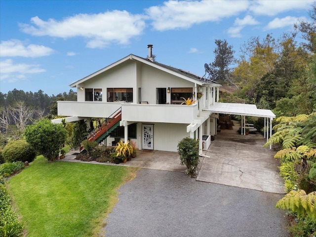 view of front of house with driveway, stucco siding, stairway, and a front yard