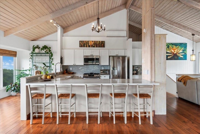 kitchen with a peninsula, hardwood / wood-style flooring, appliances with stainless steel finishes, and a sink