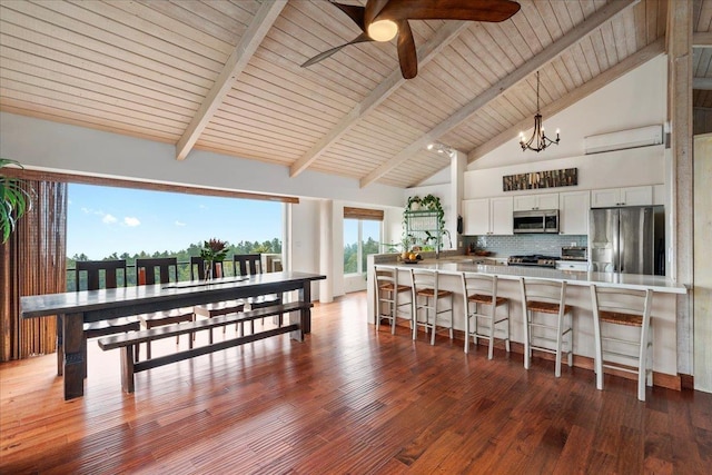 kitchen with stainless steel appliances, a breakfast bar, wood finished floors, white cabinets, and backsplash