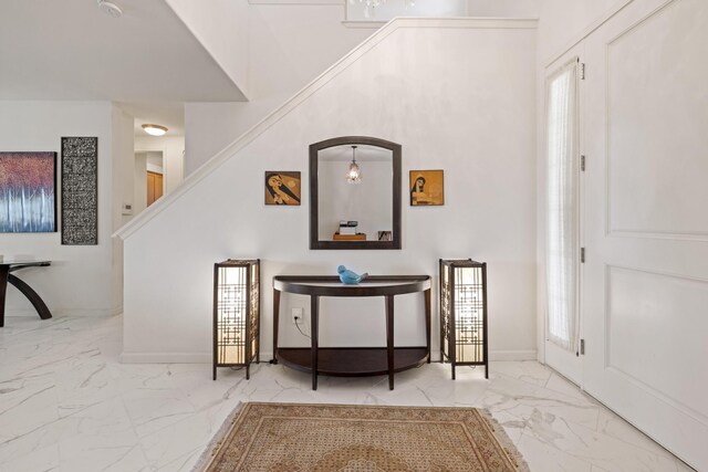 entryway with baseboards, marble finish floor, stairway, and a towering ceiling