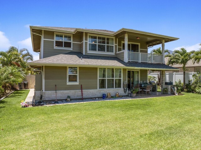 rear view of property featuring a patio area, fence, a lawn, and a balcony