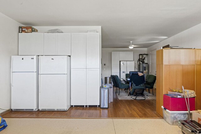 kitchen with electric water heater, freestanding refrigerator, and white cabinets