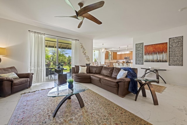 living area with marble finish floor and ceiling fan with notable chandelier