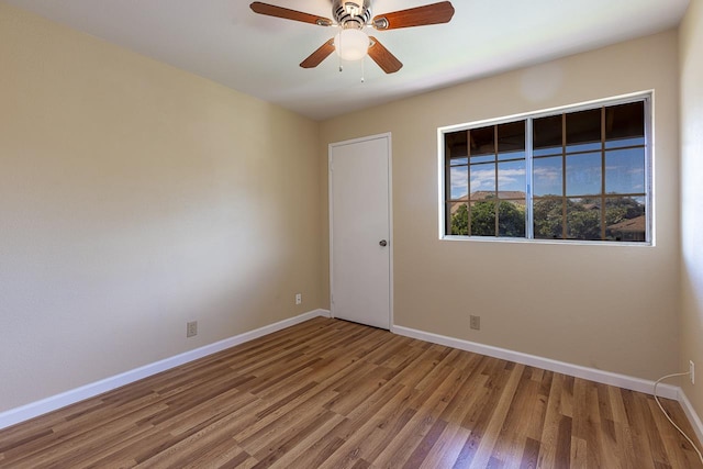 unfurnished room featuring baseboards, wood finished floors, and ceiling fan