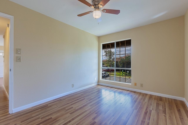empty room with a ceiling fan, wood finished floors, and baseboards