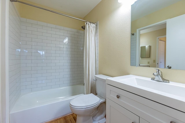 full bath featuring wood finished floors, toilet, a textured wall, vanity, and shower / tub combo with curtain