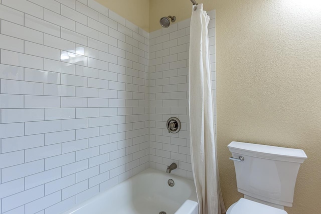 bathroom featuring shower / bathtub combination with curtain, a textured wall, and toilet