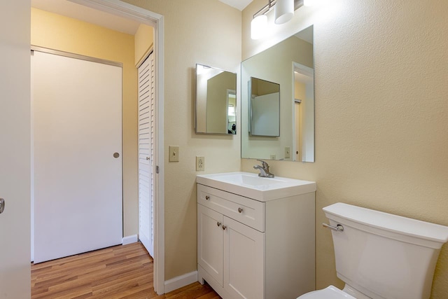 bathroom with wood finished floors, toilet, and vanity