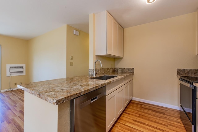 kitchen featuring a sink, light wood-type flooring, a peninsula, baseboards, and stainless steel dishwasher