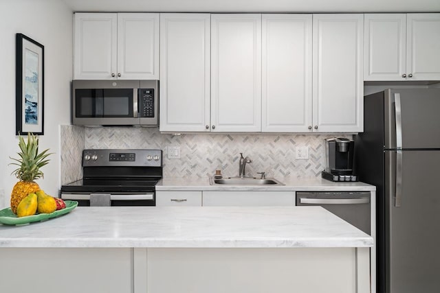 kitchen featuring light stone counters, decorative backsplash, white cabinets, a sink, and stainless steel appliances