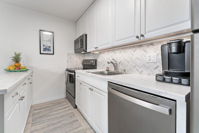 kitchen featuring stainless steel dishwasher, range with electric cooktop, backsplash, a sink, and baseboards