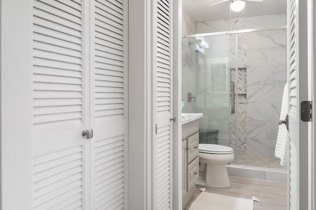 bathroom featuring toilet, vanity, a shower stall, and a closet