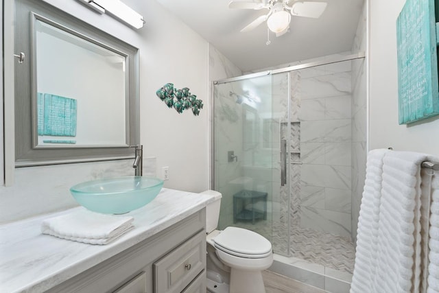 bathroom with toilet, a ceiling fan, a shower stall, and vanity